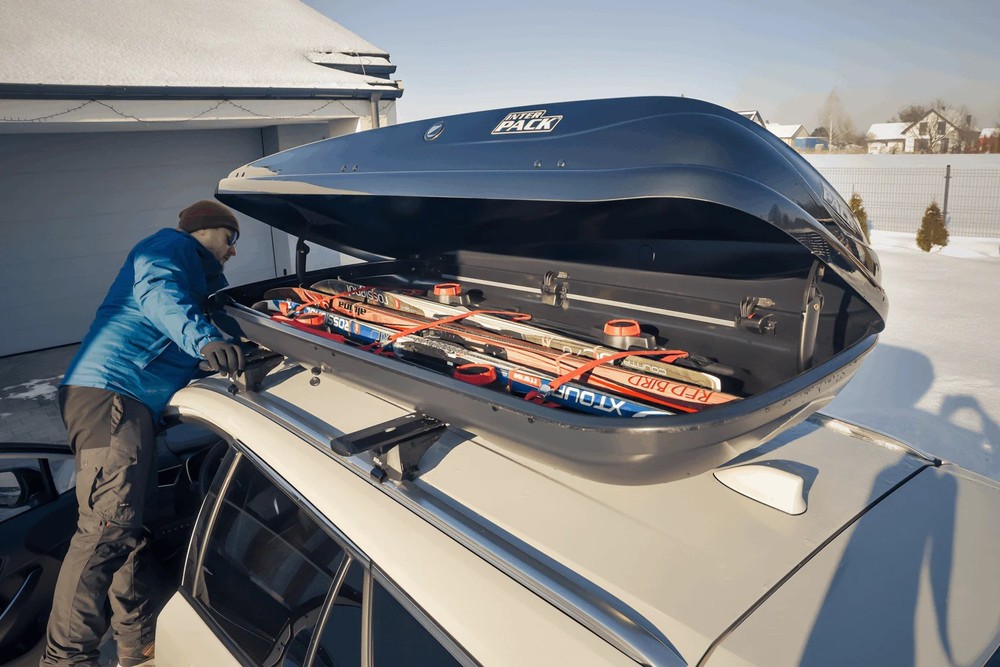 Box dachowy Inter Pack Zenith 8.6 czarny metalik 440L – zamontowany na dachu niebieskiego hatchbacka, plener miejski
