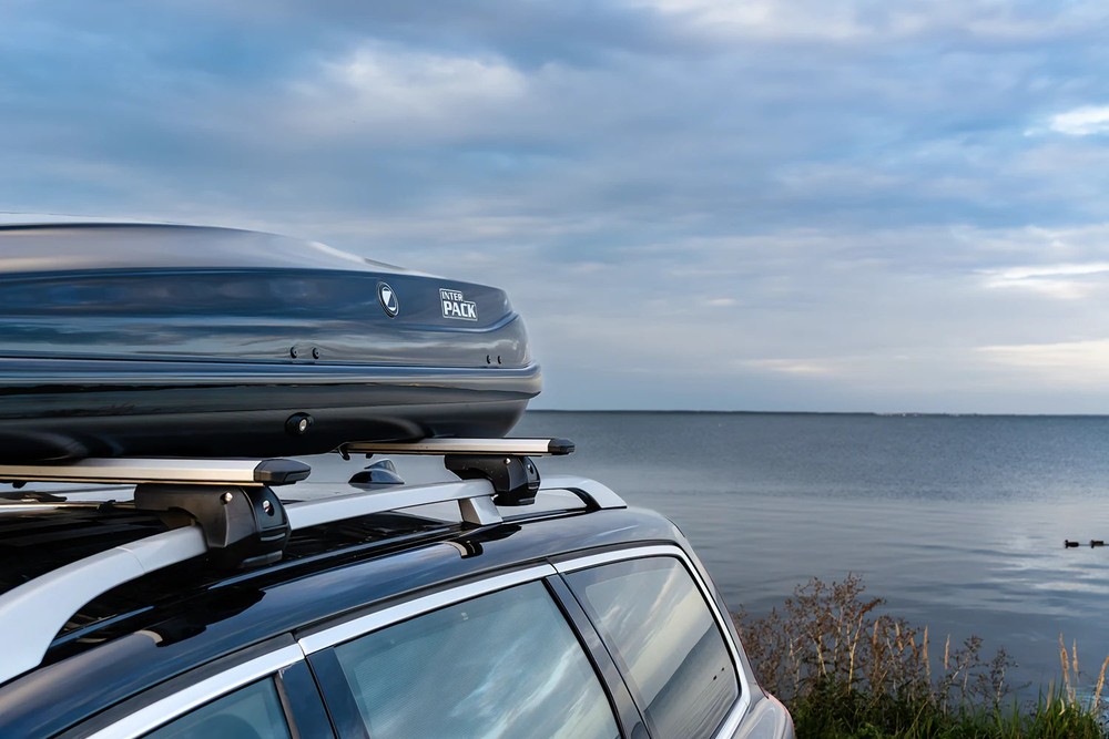 Box dachowy Inter Pack Zenith 8.6 czarny metalik 440L – zamontowany na dachu szarego SUV-a, ujęcie 3/4 z tyłu