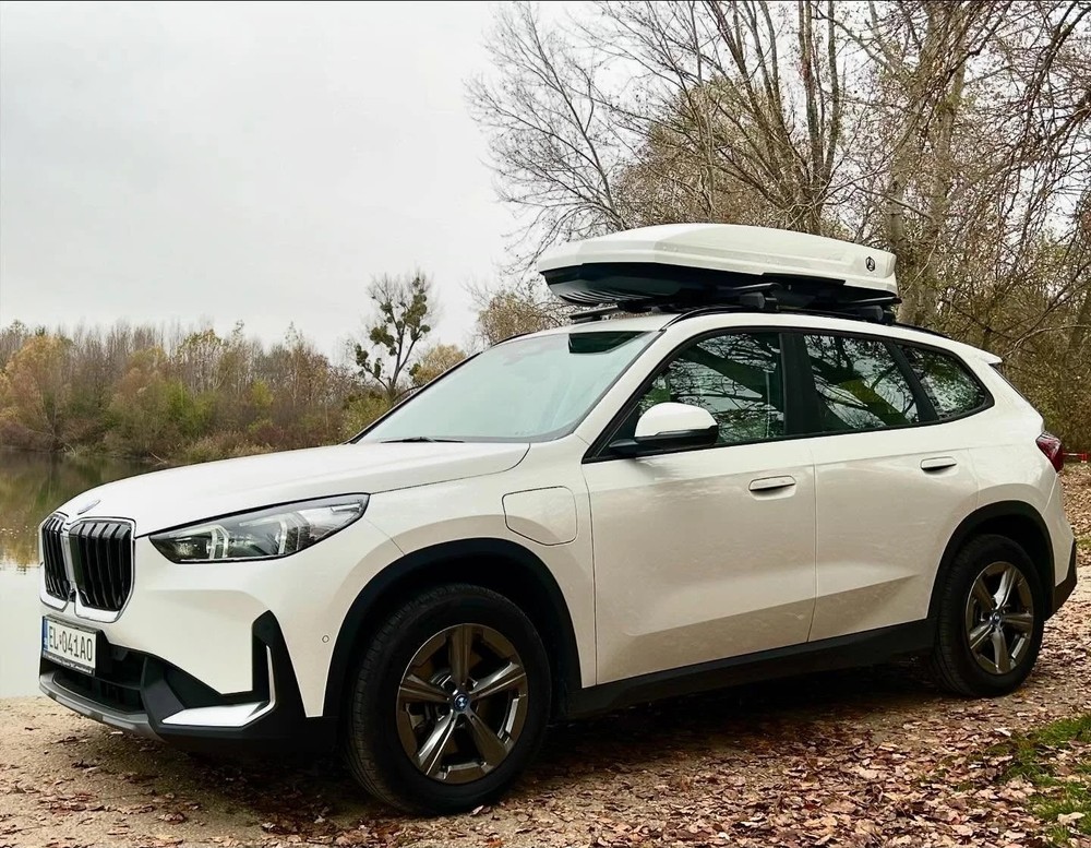 Box dachowy Northline EvoSpace TEF biały połysk zamontowany na dachu białego SUV-a nad jeziorem